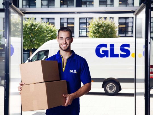 A delivery man holds packages in front of his van