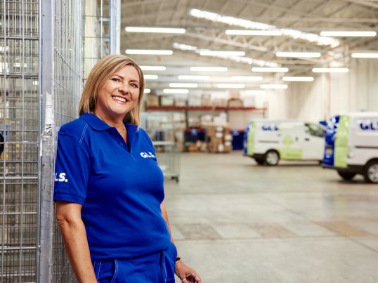A woman stands smiling in a GLS depot