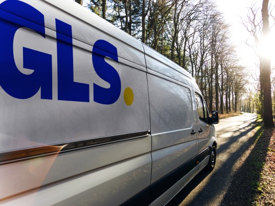 GLS parcel van driving through a forest.