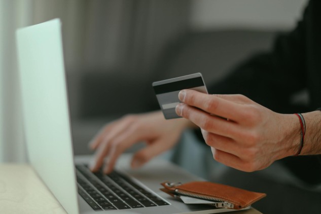 Person making an online purchase with a credit card using a laptop on an e-commerce website.