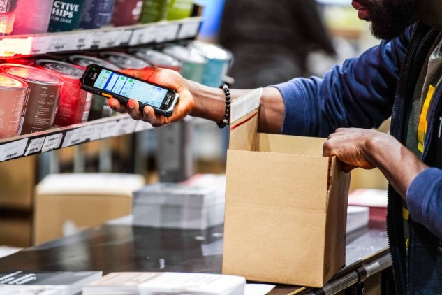 Operario escaneando productos con un dispositivo móvil mientras prepara pedidos en un centro de fulfillment para comercio electrónico.