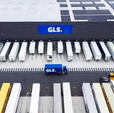 Hub logistique GLS à Paris vu du ciel, avec toit équipé de panneaux solaires et camions aux quais de chargement.